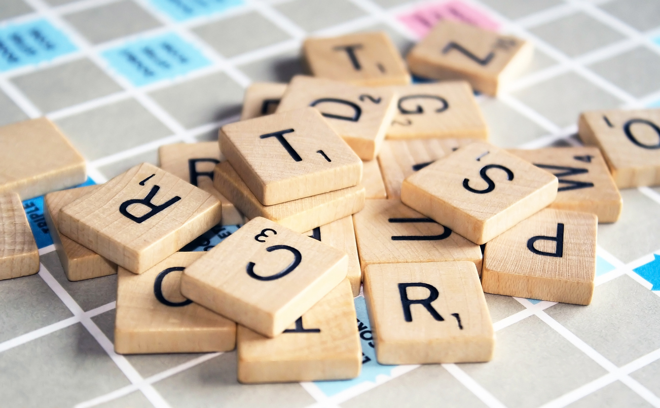 Scrabble tiles are shown scattered on a game board.
